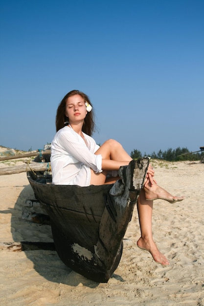 Photo jeune femme assise dans un bateau en bois noir