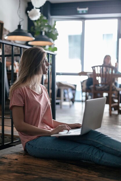 Jeune femme assise dans un café, à l'aide d'un ordinateur portable