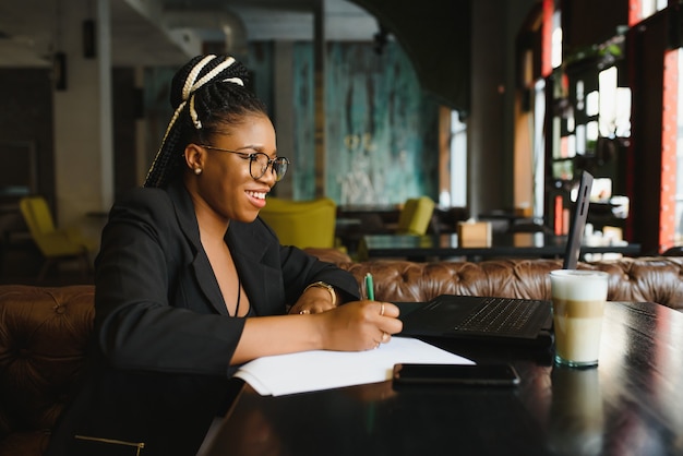 Jeune femme assise dans un café écrit sur papier