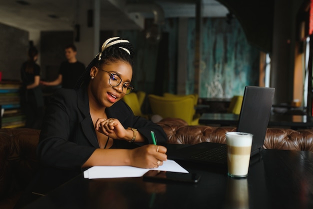 Jeune femme assise dans un café écrit sur papier