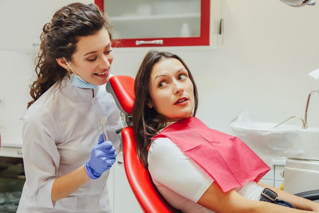 Une jeune femme assise dans un fauteuil dentaire pour le rendez-vous d'un médecin pendant ce temps elle était très inquiète de la peur puis en regardant dans le téléphone