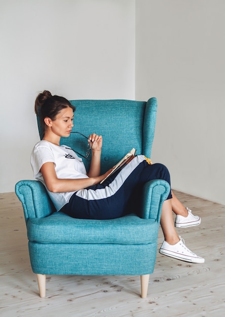 Jeune femme assise dans le fauteuil et livre de lecture