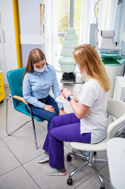 Jeune femme assise dans un fauteuil regardant une lampe à fente lors d'un examen médical dans les yeux