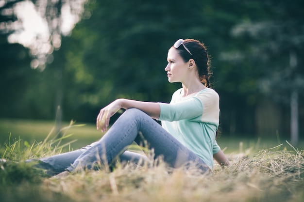 Jeune femme assise sur l'herbe dans le parc. les gens et la nature