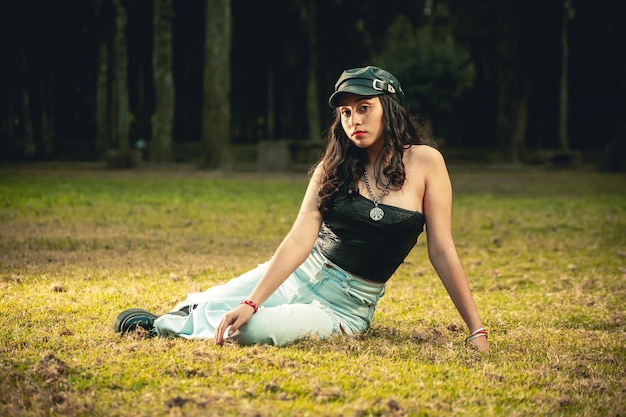 Jeune femme assise sur l'herbe portant un chapeau et des vêtements décontractés