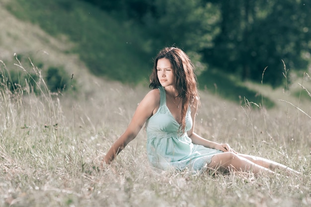 jeune femme assise sur l'herbe d'une prairie d'été