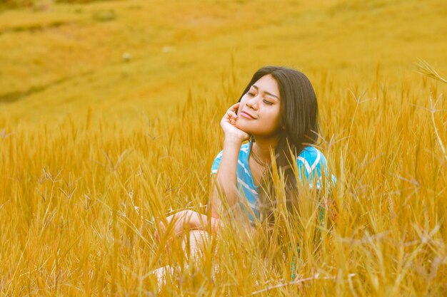 Jeune femme assise sur l'herbe séchée à l'automne