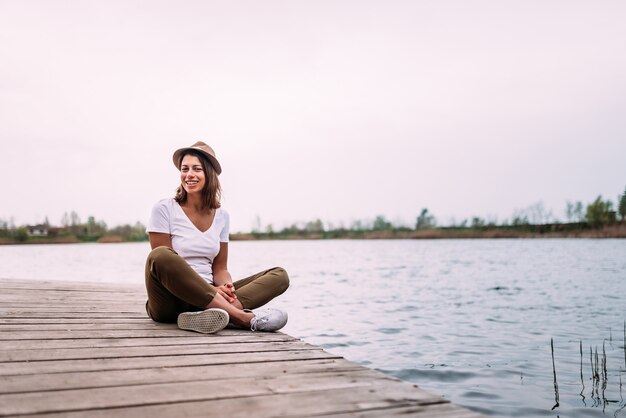 Jeune femme assise sur une jetée en bois, se détendre.