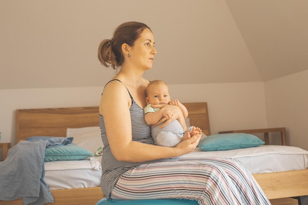 Une jeune femme assise sur le lit à la maison.