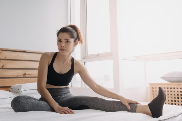 Une jeune femme assise sur le lit à la maison.