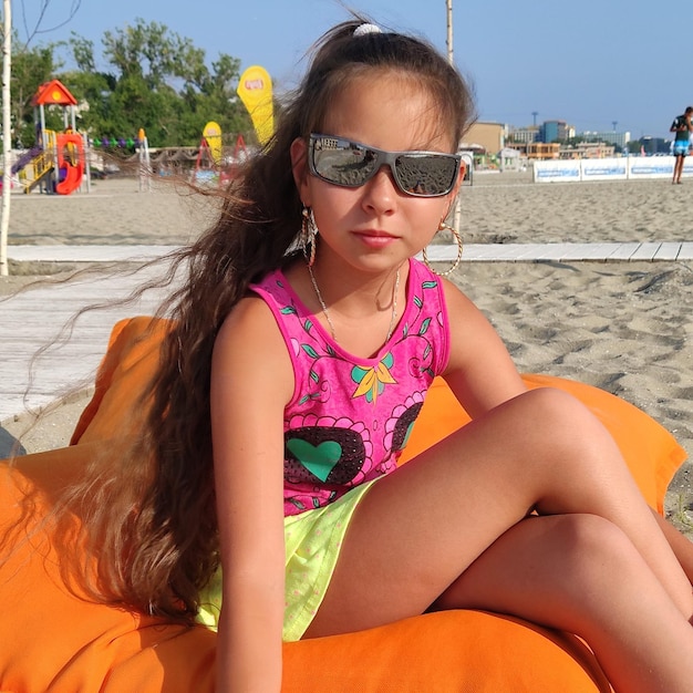 Une jeune femme assise sur des lunettes de soleil sur la plage