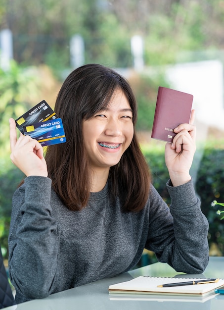 Jeune femme assise montrant passeport et carte de crédit