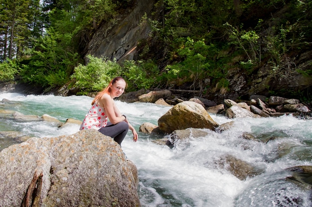 Jeune femme assise sur une pierre près de la rivière