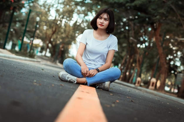 Une jeune femme assise sur une plante contre des arbres.