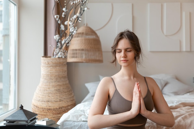 jeune femme assise à la pose de yoga à la maison