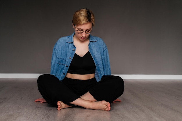 Jeune femme assise en posture de lotus sur le sol méditant à l'intérieur Fille faisant des exercices de yoga en studio