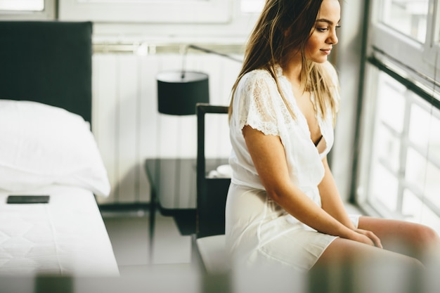 Jeune femme assise près de la fenêtre dans la chambre