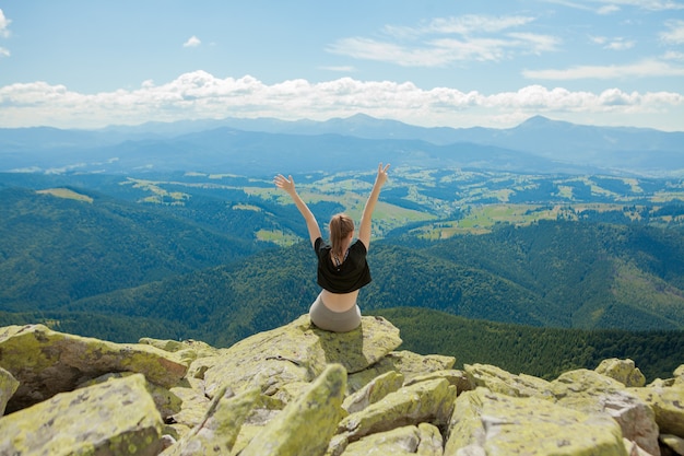 Jeune femme assise sur un rocher et regardant à l'horizon.