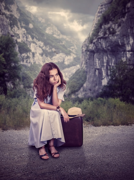 Jeune femme assise sur sa valise.