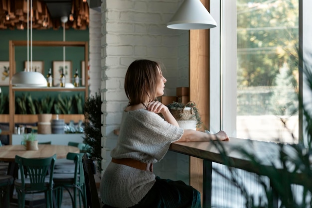 Jeune femme assise seule dans un café près de la fenêtre Jolie femme se détend dans un café à l'intérieur