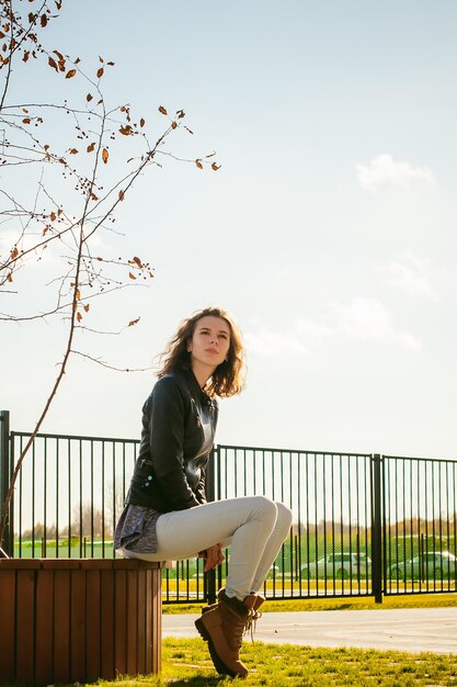 Photo une jeune femme assise sur un siège en ville contre le ciel