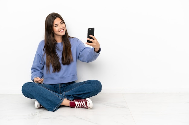 Jeune femme assise sur le sol faisant un selfie