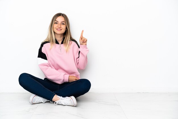 Jeune femme assise sur le sol à l'intérieur montrant une excellente idée