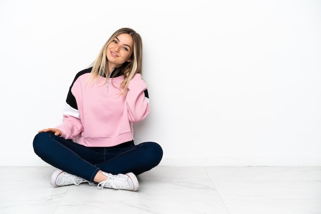 Jeune femme assise sur le sol à l'intérieur en riant