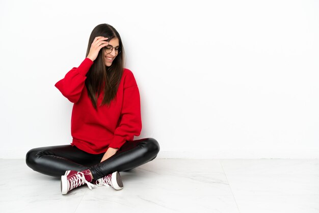 Jeune femme assise sur le sol isolé sur fond blanc en riant