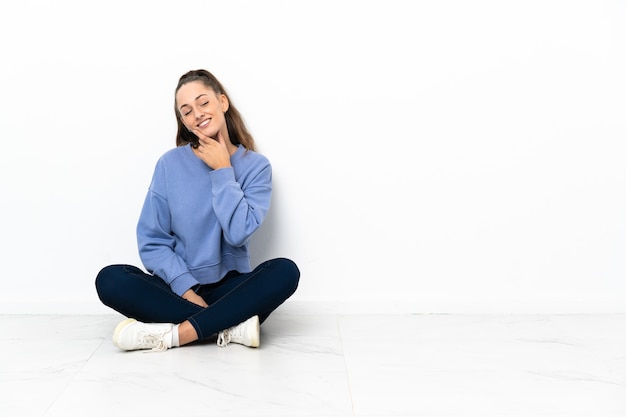 Jeune femme assise sur le sol regardant sur le côté et souriant