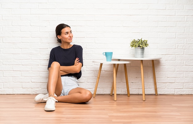 Jeune femme assise sur le sol, regardant de côté