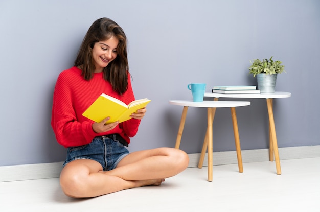 Jeune femme assise sur le sol et tenant un cahier