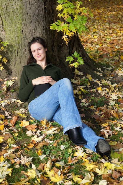 Jeune femme assise sous un arbre en automne