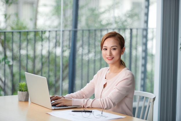 Jeune femme assise à la table de bureau avec ordinateur portable.