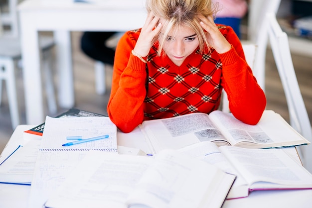 Photo jeune femme assise à table avec des livres