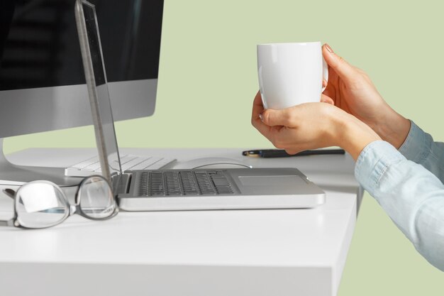 Jeune femme assise à la table avec un netbook ouvert. Personne de sexe féminin utilisant la technologie moderne.