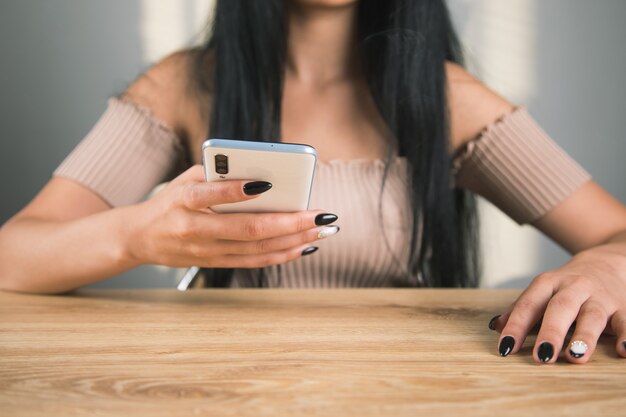 Jeune femme assise à la table avec le téléphone