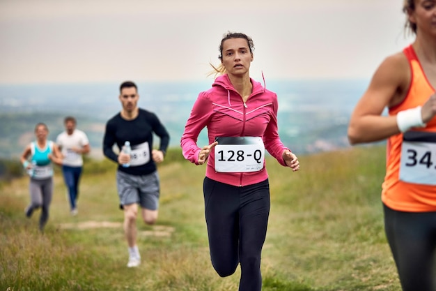 Jeune femme athlétique courant tout en participant à une course de marathon dans la nature