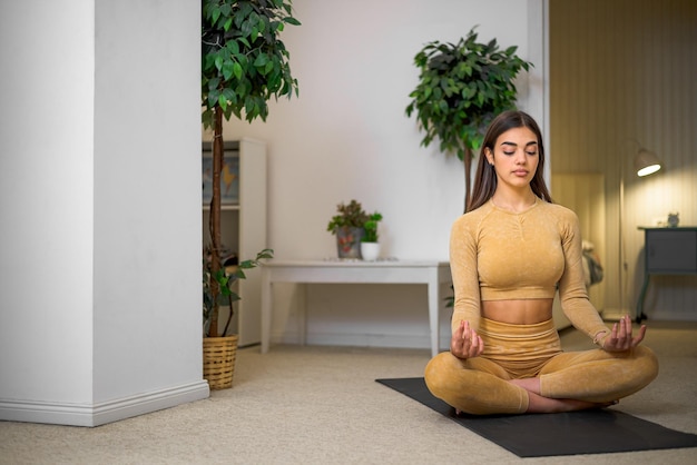 Jeune femme athlétique détendue assise sur un tapis de fitness à l'intérieur Femme faisant des exercices de yoga