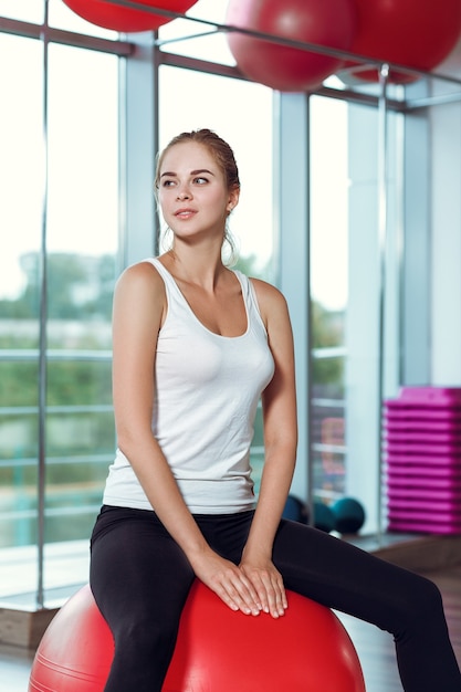 Jeune femme athlétique faisant des exercices avec ballon de fitness dans la salle de gym