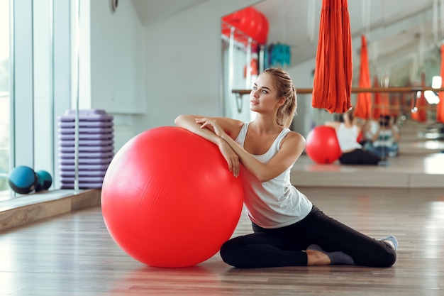 Jeune femme athlétique faisant des exercices avec ballon de fitness dans la salle de gym