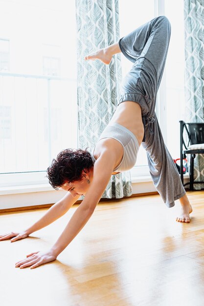 Jeune femme athlétique faisant des exercices d'étirement dans le salon. Yoga à domicile,