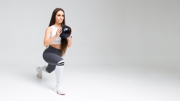 Jeune femme athlétique faisant des mouvements brusques tenant un médecine-ball dans ses mains