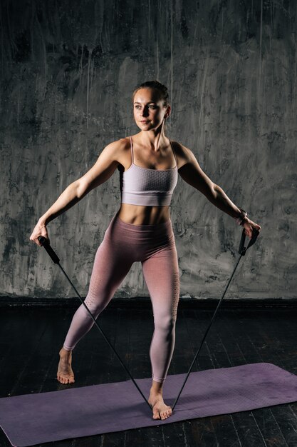 Jeune femme athlétique musclée avec un beau corps portant des vêtements de sport faisant de l'exercice avec une bande de résistance