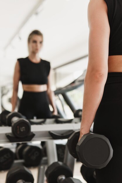 Jeune femme athlétique pendant son entraînement de remise en forme avec des haltères en salle de sport