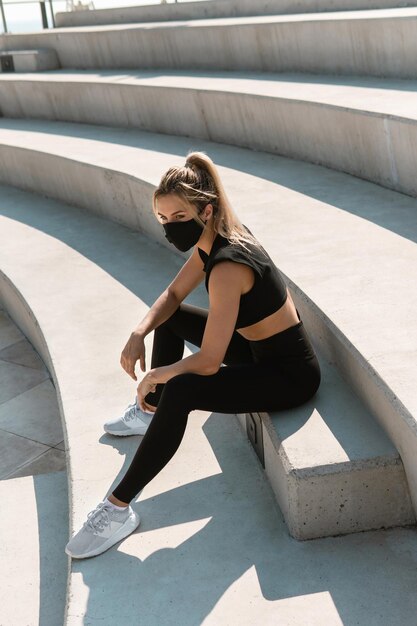 Jeune femme athlétique portant un masque facial pendant l'entraînement de rue d'été