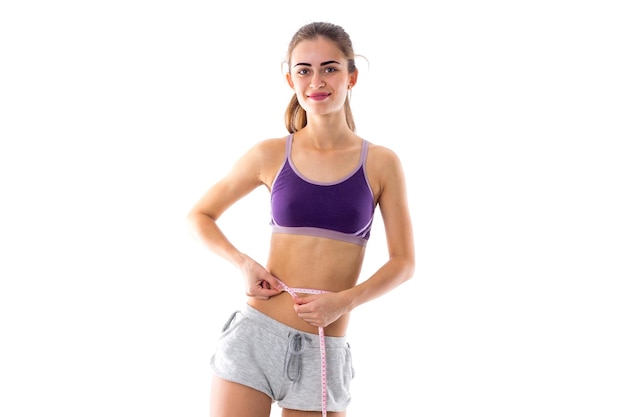 Jeune femme athlétique portant un short gris avec queue de cheval debout en arrière et montrant ses biceps