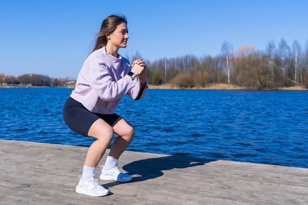 Une jeune femme athlétique s'accroupit pendant une séance d'entraînement