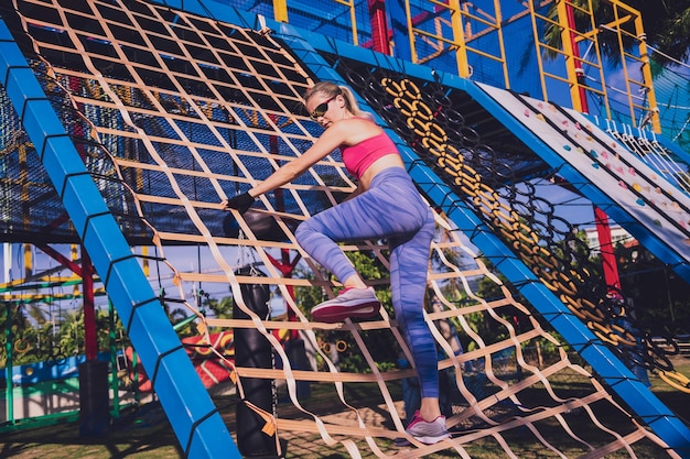 Jeune femme athlétique s'entraînant et grimpant au camp d'entraînement