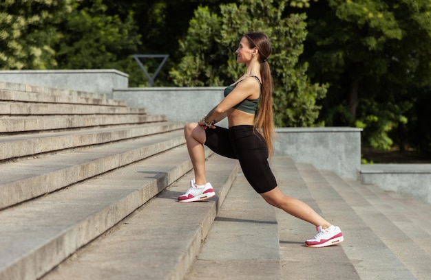 Une jeune femme athlétique s'entraîne à étirer les jambes sur les escaliers Entraînement en plein air